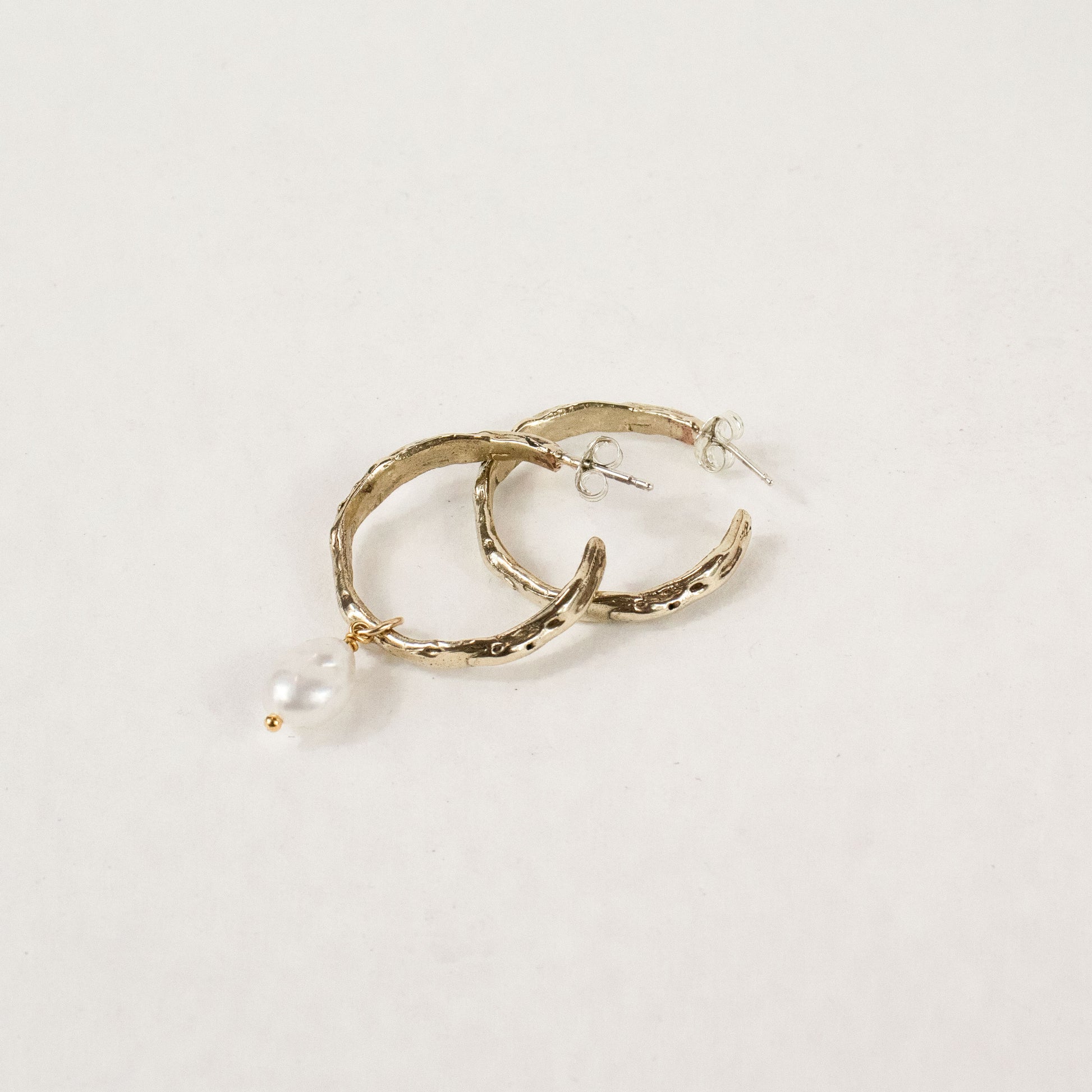 Brass melted hoop earrings available in 1 inch and 0.5 inch diameters with one freshwater pearl and sterling silver posts and backings handmade and finished in our Catskills store-studio