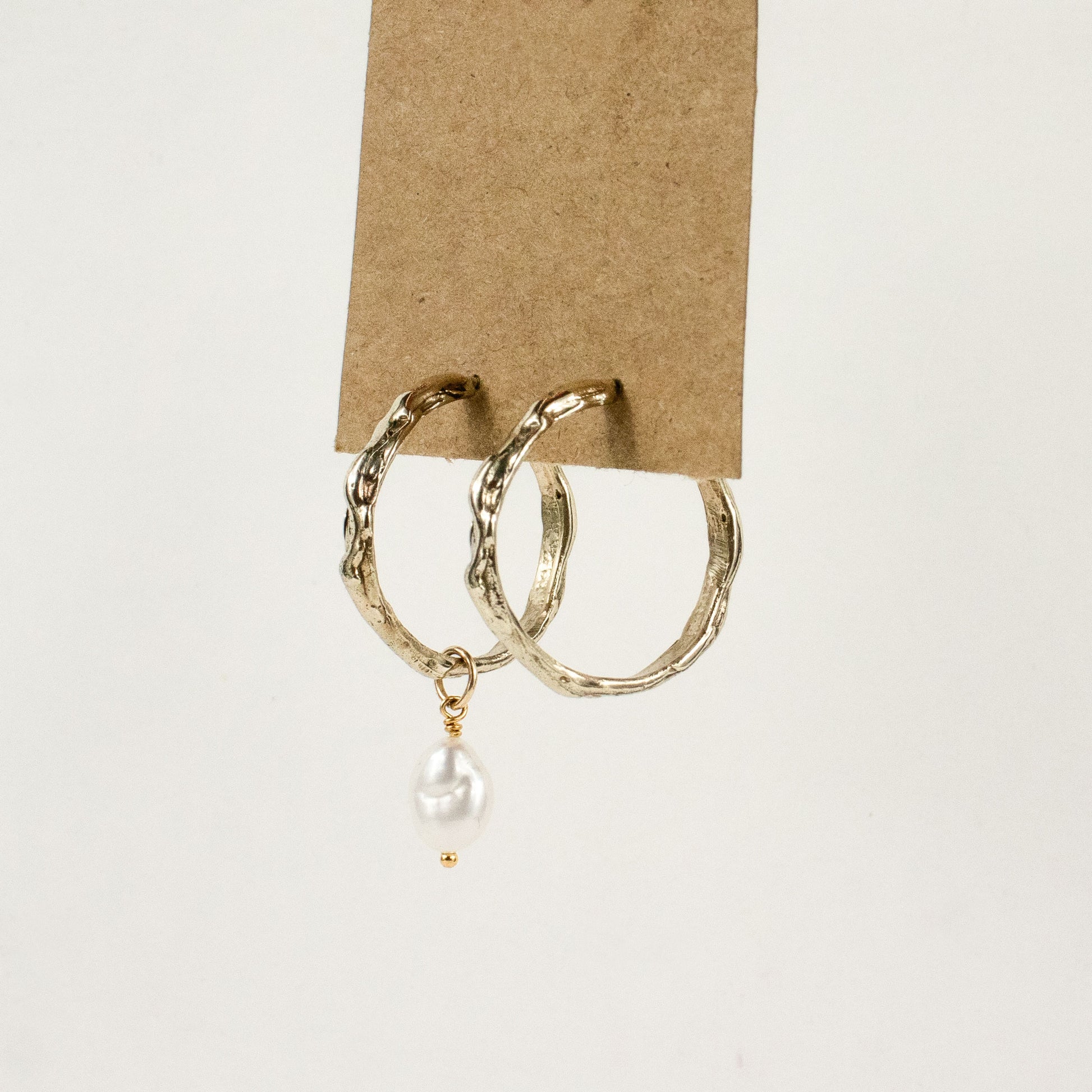 Brass melted hoop earrings available in 1 inch and 0.5 inch diameters with one freshwater pearl and sterling silver posts and backings handmade and finished in our Catskills store-studio