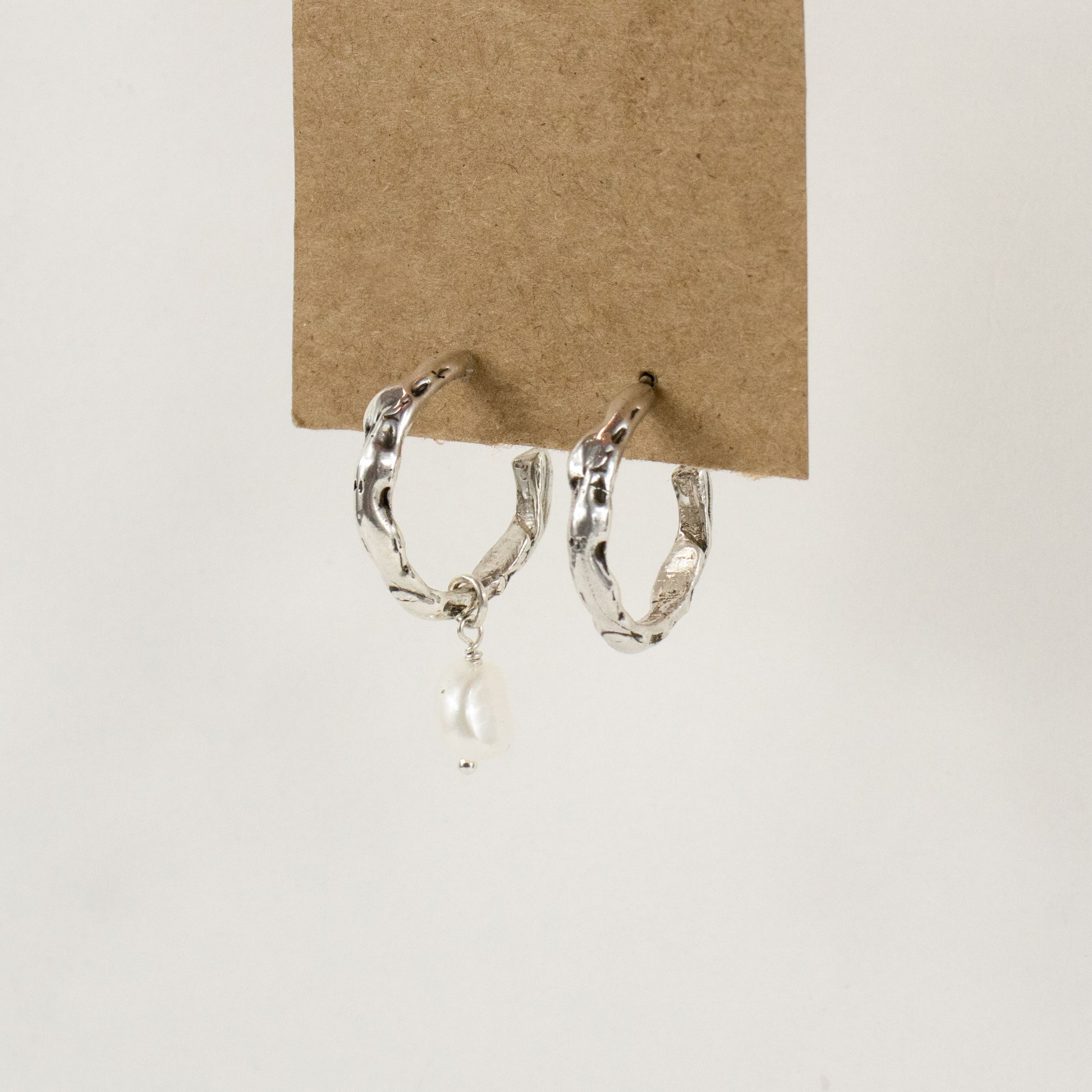 Sterling silver melted hoop earrings available in 1 inch and 0.5 inch diameters with one freshwater pearl handmade and finished in our Catskills store-studio