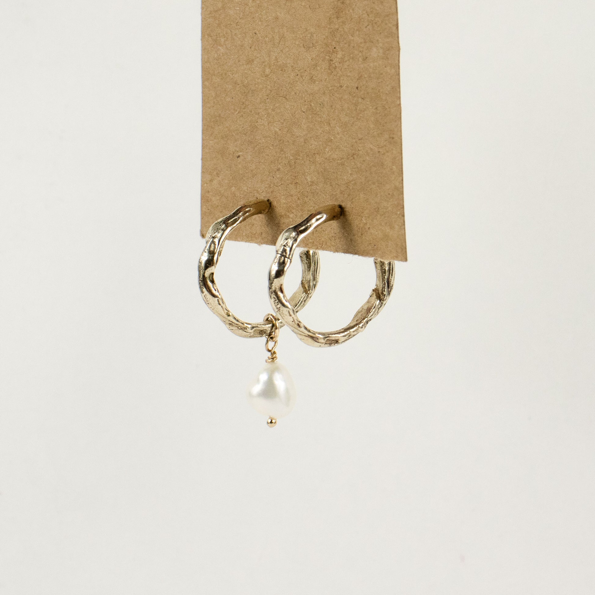 Brass melted hoop earrings available in 1 inch and 0.5 inch diameters with one freshwater pearl and sterling silver posts and backings handmade and finished in our Catskills store-studio