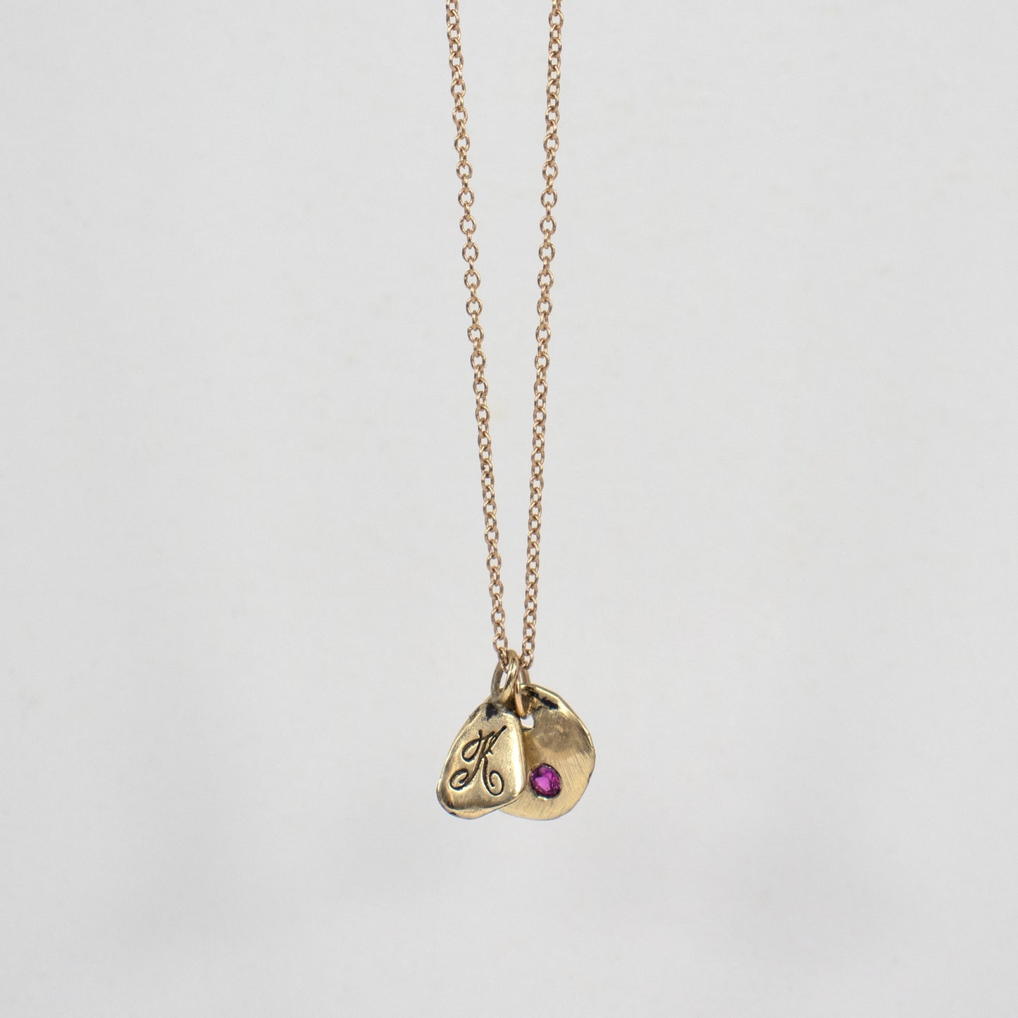 Solid reclaimed 14k gold signature Kria tag and Maine rock 0.5 inch in diameter set with 2mm hot pink sapphire on an 18 inch 14k fine cable-chain.  Made-to-order and finished in our Catskills store-studio.