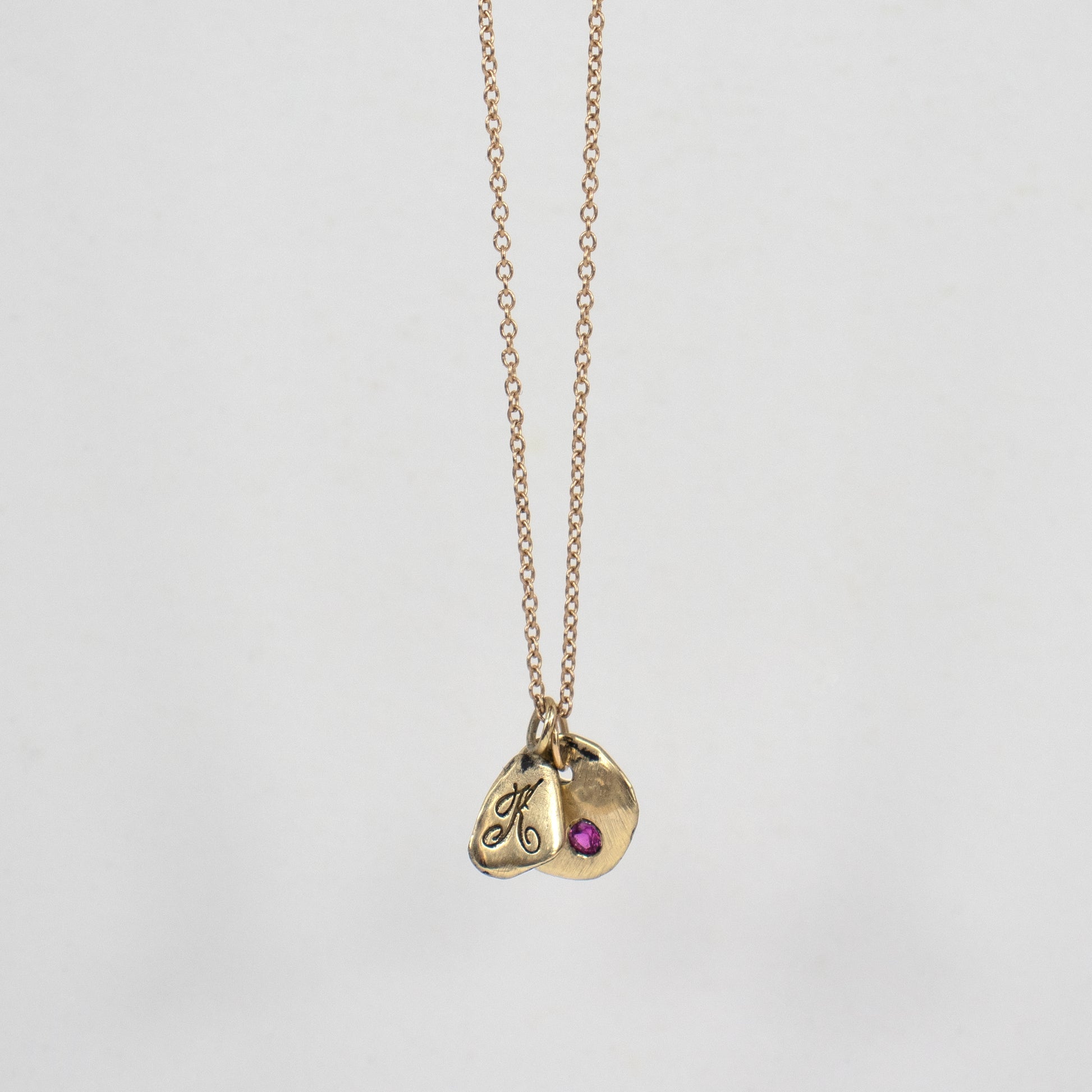 Solid reclaimed 14k gold signature Kria tag and Maine rock 0.5 inch in diameter set with 2mm hot pink sapphire on an 18 inch 14k fine cable-chain.  Made-to-order and finished in our Catskills store-studio.