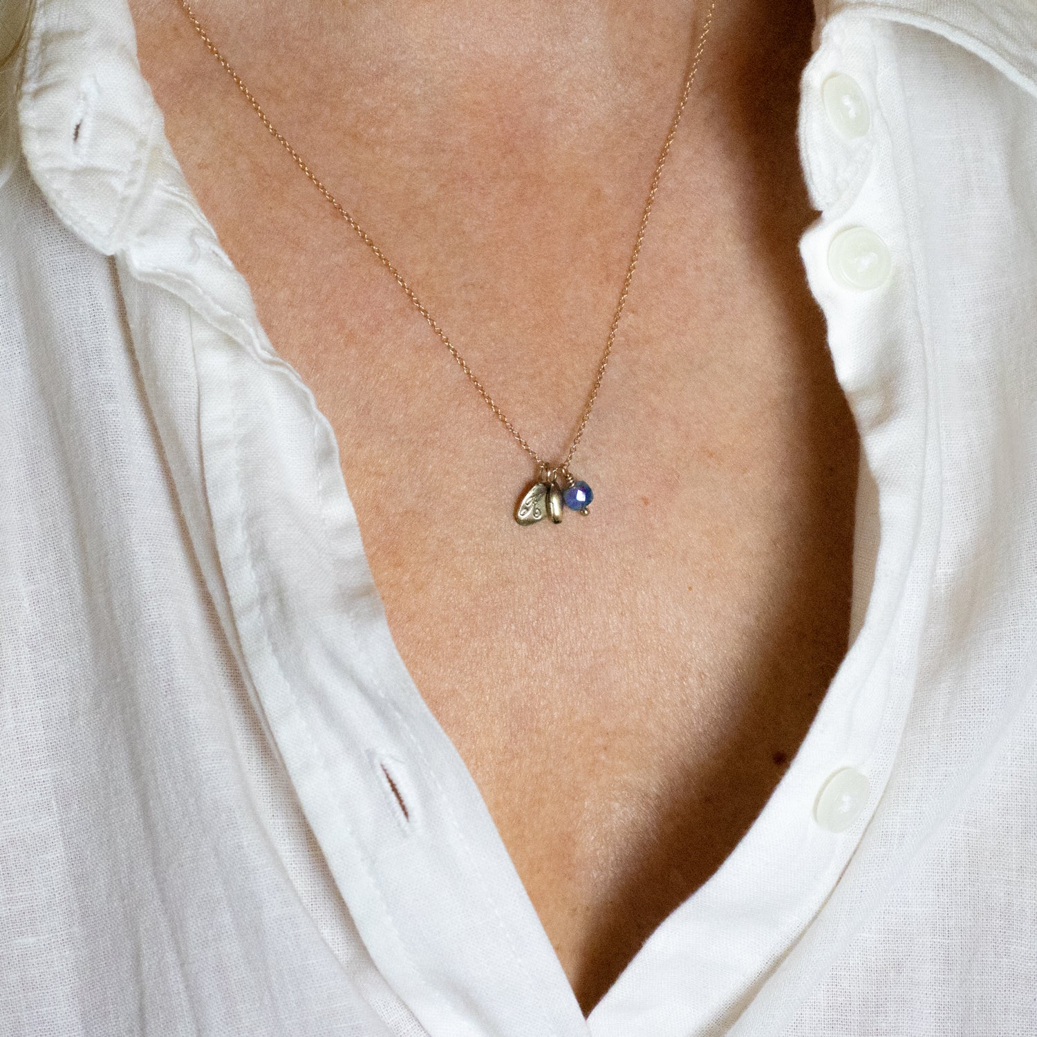 Solid reclaimed 14k gold seed with 4mm blue sapphire bead and 14k Kria signature tag on an 18 inch on 14k fine cable-chain. Handmade and finished in our Catskills store-studio shown on model.