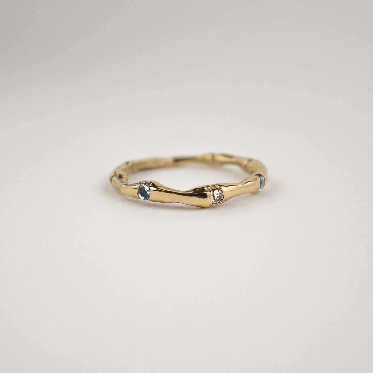 14k gold ring cast from a muskrat spine set with one 2 mm diamond between two 2 mm blue sapphires shown on off-white background by Kria World jewelry