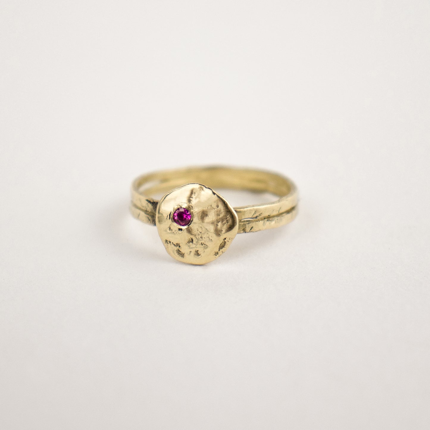 Hammer-finished solid reclaimed 14k gold Maine rock 0.5 inch in diameter set with one 2mm pink sapphire.  Made-to-order and finished in our Catskills store-studio.
