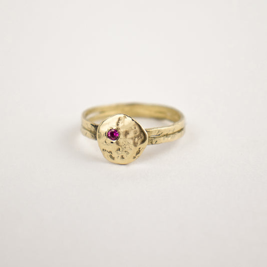 Hammer-finished solid reclaimed 14k gold Maine rock 0.5 inch in diameter set with one 2mm pink sapphire.  Made-to-order and finished in our Catskills store-studio.
