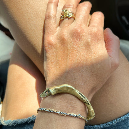 Fish jaw cuff with sterling silver Kria tag and chain handmade and finished in our Catskills store-studio shown on wrist with gold rings on hand.