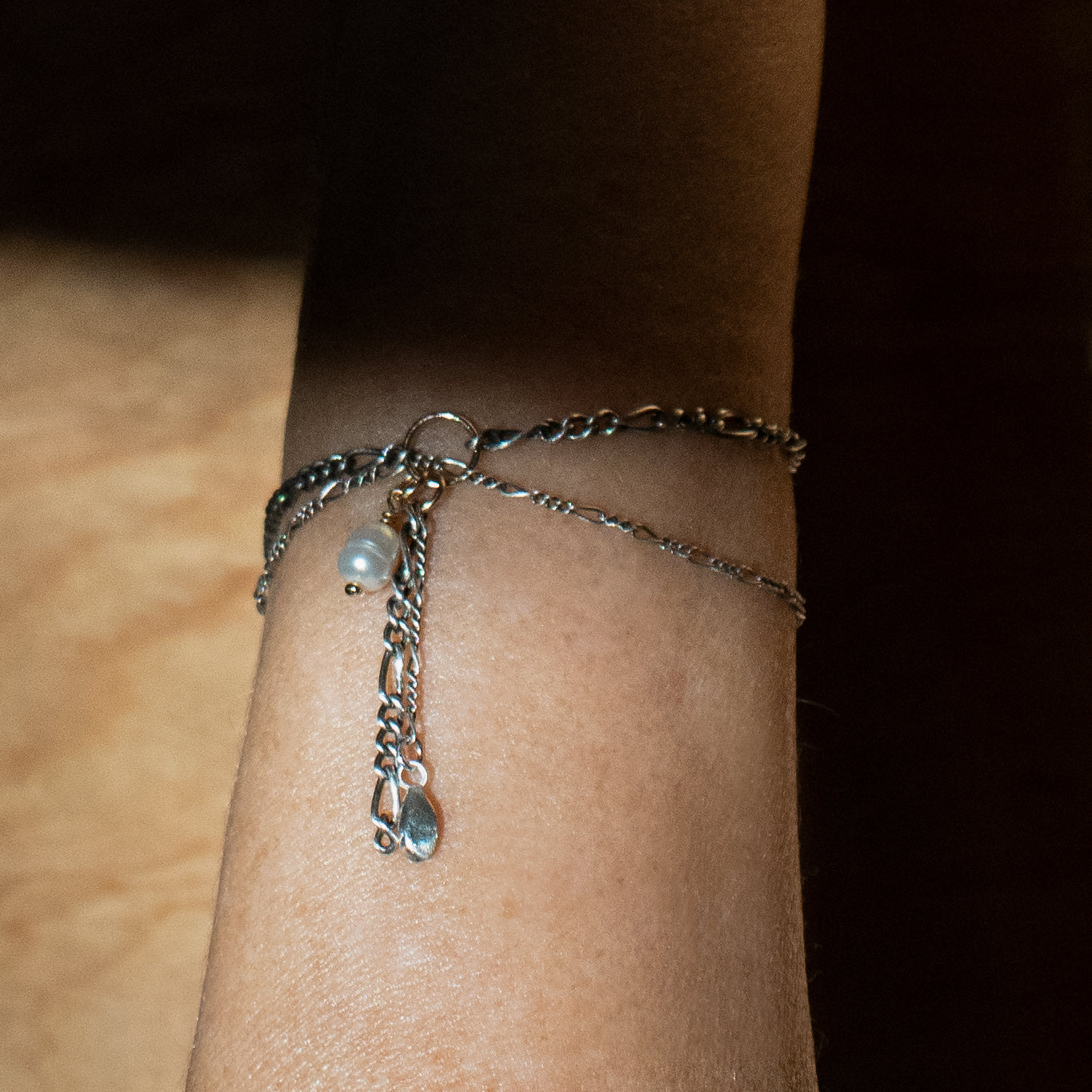 Solid reclaimed sterling silver seed and freshwater pearl on asymmetrical double sterling Figaro chain handmade and finished in our Catskills store-studio on model's wrist.