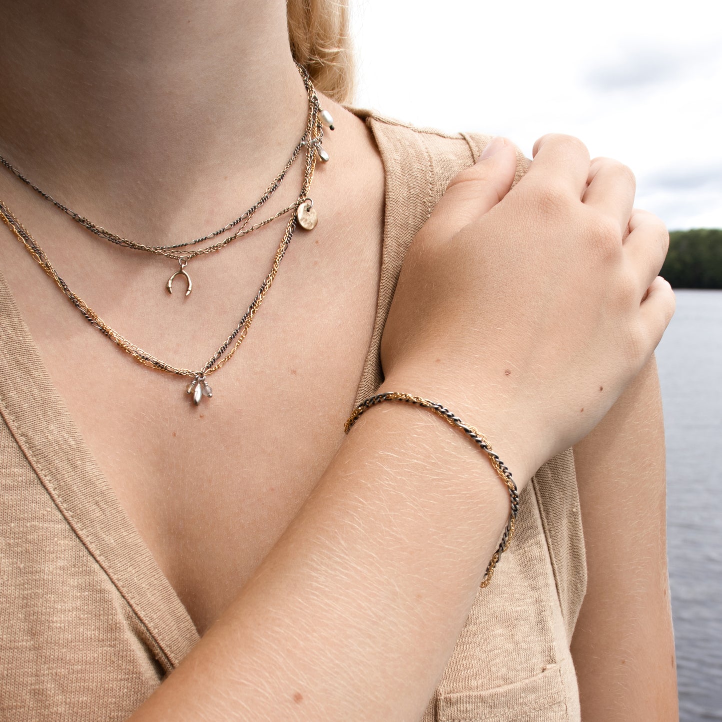 Hand-threaded sterling silver and gold-filled mixed-chain bracelet 7 inches in diameter with our signature sterling silver Kria tag shown on model in front of lake