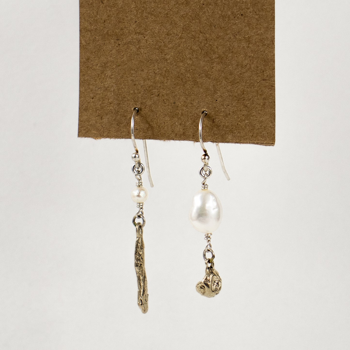 Asymmetric earrings of solid brass seaweed pods with freshwater pearls dangling from sterling silver hooks and handmade and finished in our Catskills store-studio