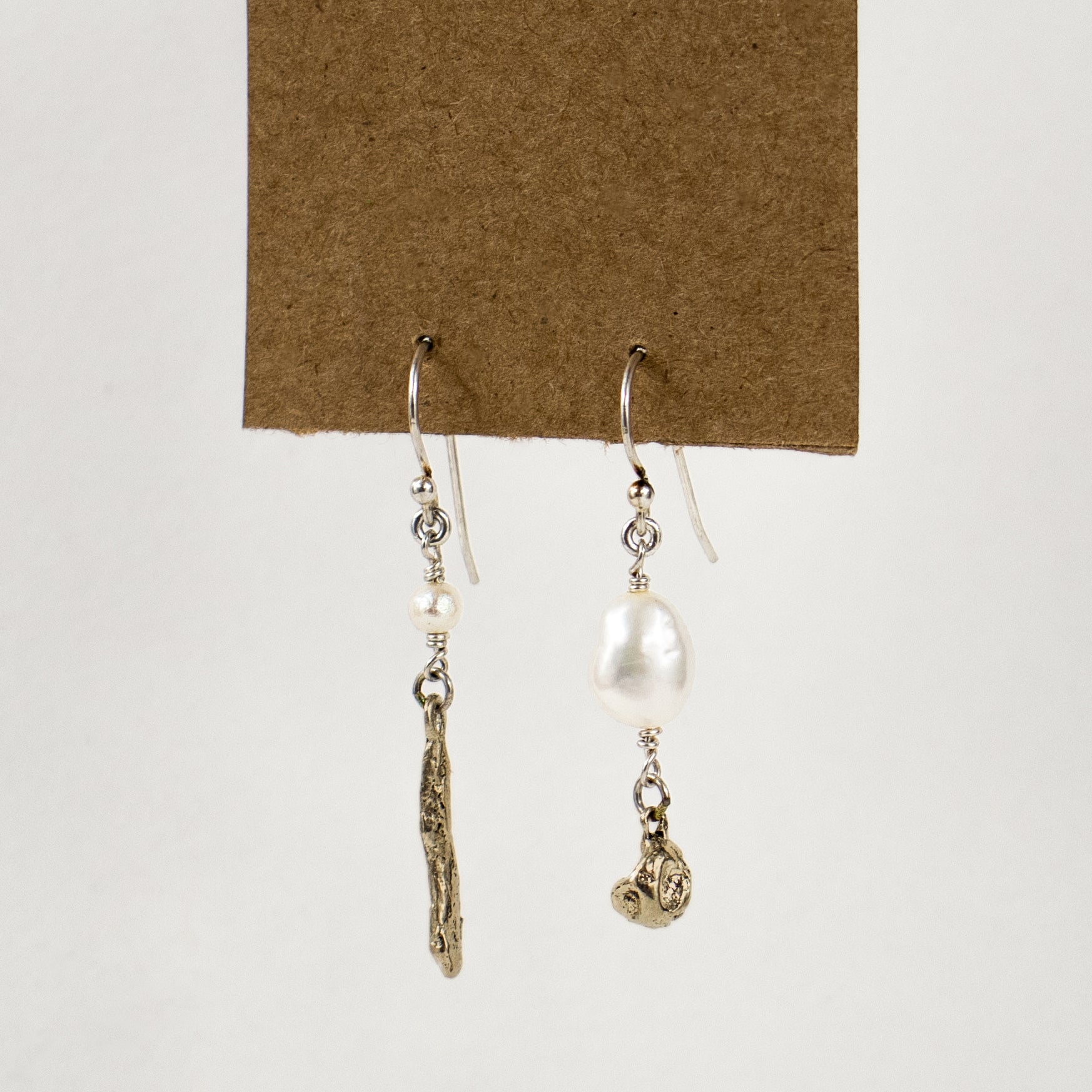 Asymmetric earrings of solid brass seaweed pods with freshwater pearls dangling from sterling silver hooks and handmade and finished in our Catskills store-studio