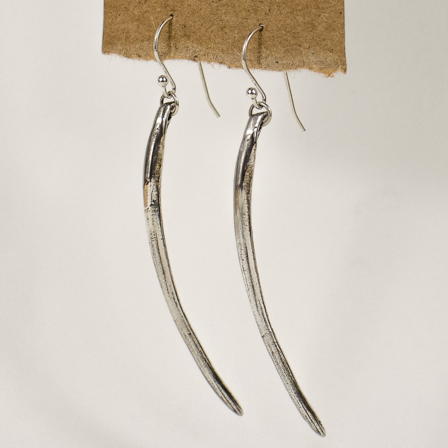 Solid reclaimed sterling silver or brass Cod branchiostegal measuring 2.25 inches in length dangling from a sterling hook and jump-ring. Handmade and finished in our Catskills store-studio.