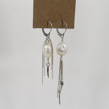 Asymmetrical sterling silver hoop earrings with two large freshwater pearls and one tiny black pearl with gold-filled and silver double mixed-chain tassels 2 and 3 inches each shown on paper tag on white background.