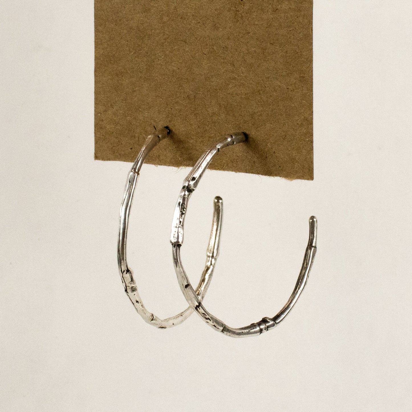 Solid sterling silver branch hoop earrings measuring 2 inches in diameter with sterling silver posts and handmade and finished in the Catskills store-studio.