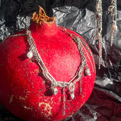 Reclaimed sterling silver seaweed pods, tangled silver chain, and freshwater pearls on sterling mixed-chain bracelet in still life with pomegranate.