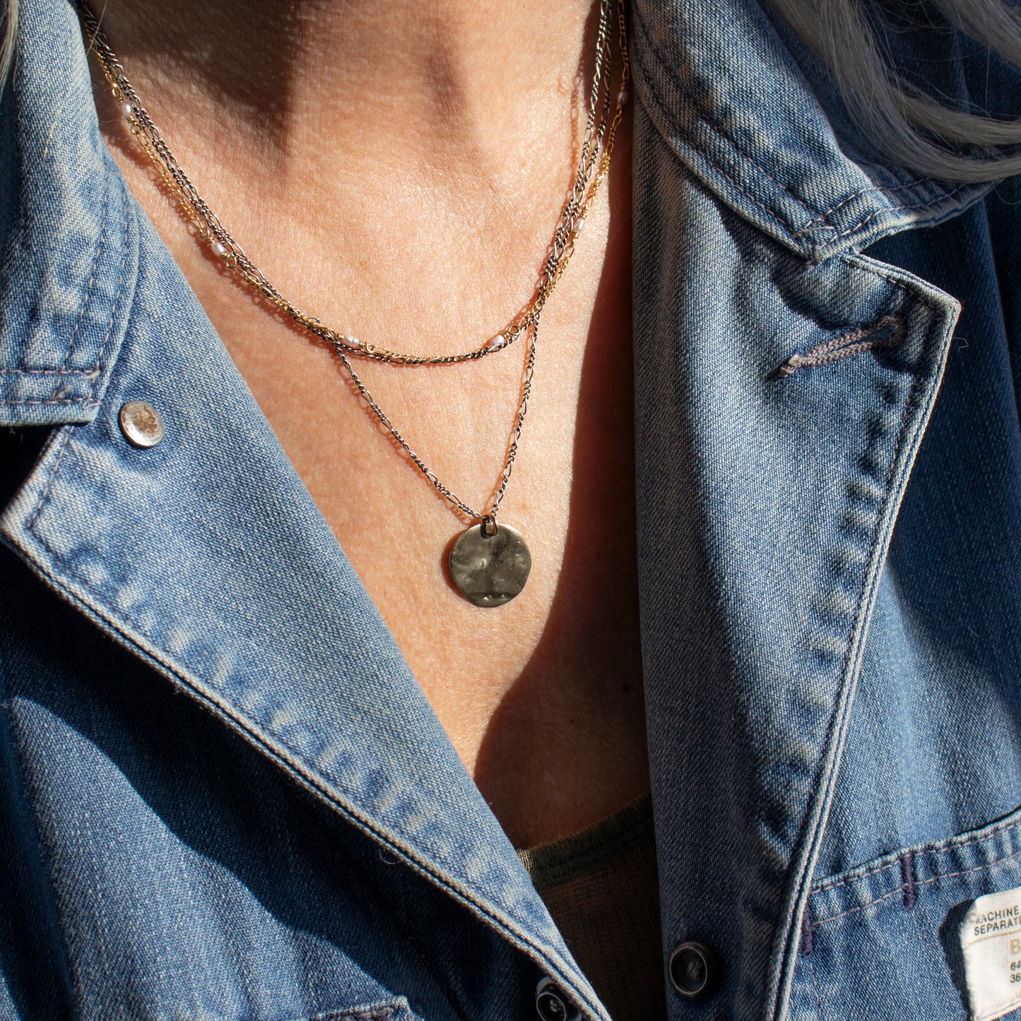 Your choice of solid reclaimed 10k gold or sterling silver hammer-finished shell pendant 0.75 inches in diameter on sterling Figaro chain adjustable 18 - 22 inches and handmade and finished in our Catskills store-studio shown on model.