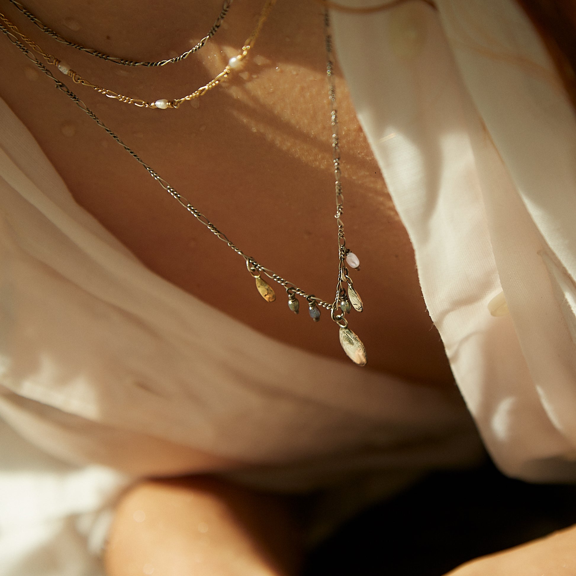 Solid reclaimed 10k gold and double sterling silver seeds on sterling Figaro chain hand-beaded with 2 mm white and peacock freshwater pearls and adjustable 16 - 20 inches handmade and finished in our Catskills store-studio shown on model.