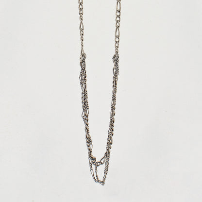 Tangled sterling silver mixed Figaro chains adjustable 20 - 22 inches shown hanging over off-white background by Kria Jewelry.