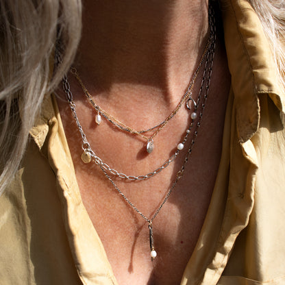 Solid reclaimed partially oxidized sterling silver spike and freshwater pearl on sterling mixed-chain adjustable 16-20 inches handmade and finished in our Catskills store-studio shown on model with necklaces in sunlight.