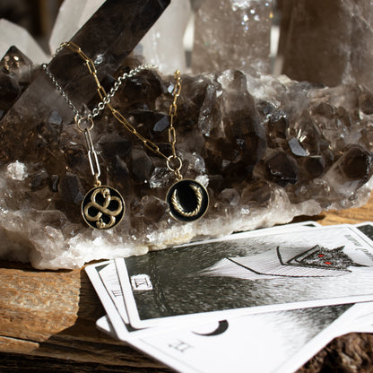 Enameled solid reclaimed 10k gold Serpent Infinity Knot charm 20 mm in diameter in your choice of black, lemon cream, or fire red enamel on adjustable 18 - 22 inch sterling silver mixed-chain handmade and finished in our Catskills store-studio shown in still life with smokey quartz geode.