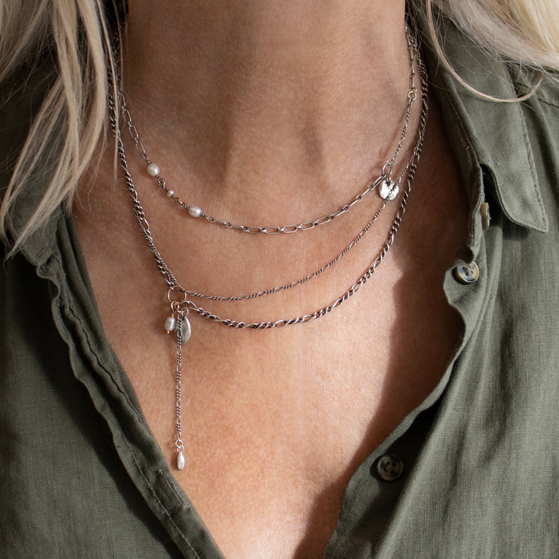 Two solid reclaimed sterling silver seeds and freshwater pearl on adjustable 16 - 20 inch asymmetrical double sterling Figaro chains handmade and finished in our Catskills store-studio shown on model with necklace.