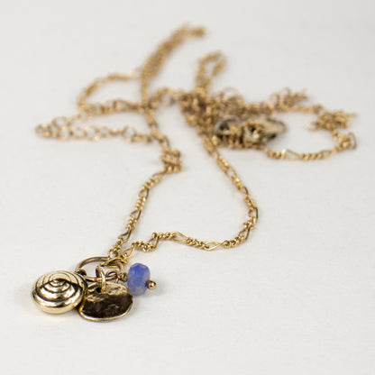 Solid reclaimed 10k gold spiral snail shell and rock disc charms with baby blue sapphire bead on gold-filled Figaro chain adjustable 18 -22 inches handmade and finished in our Catskills store-studio.