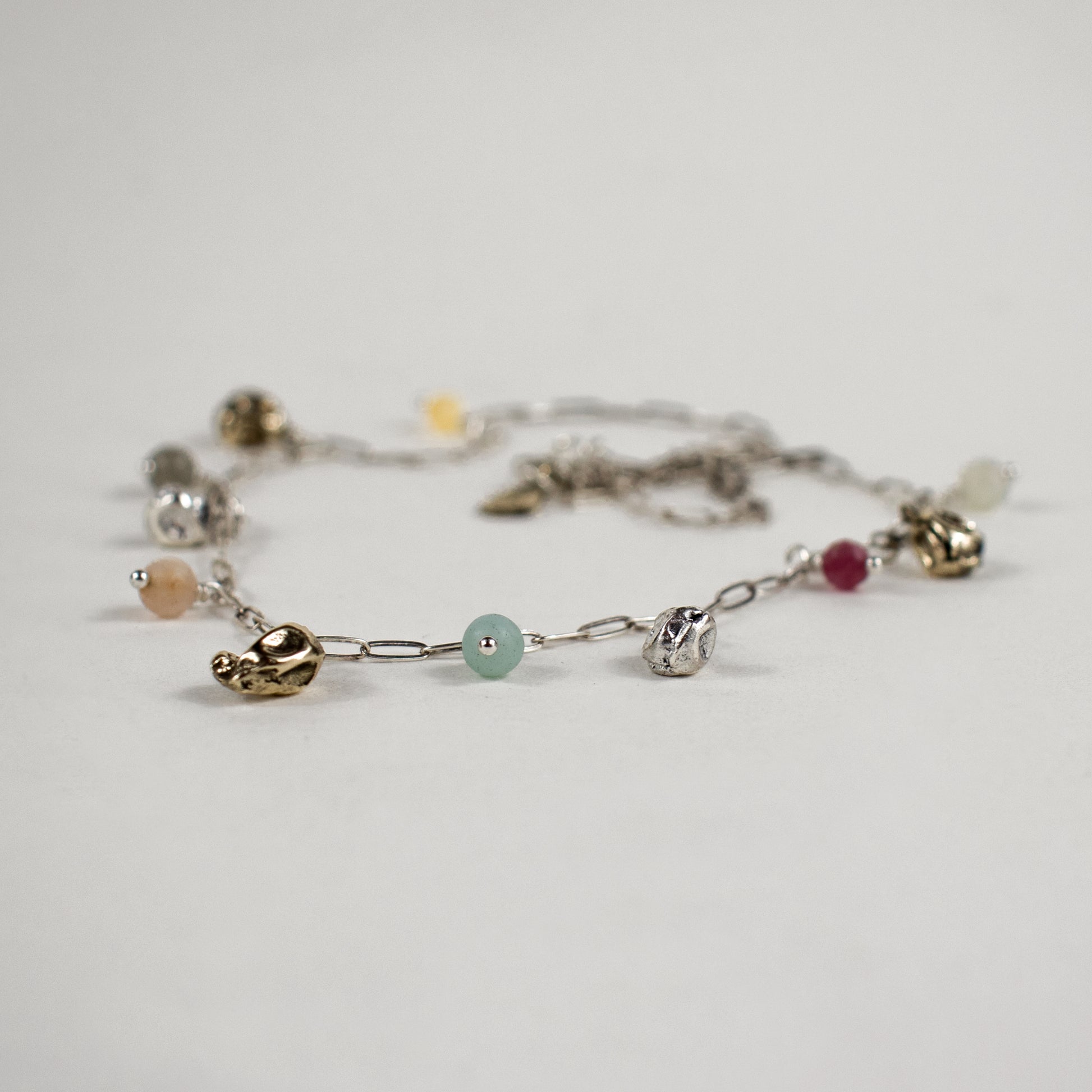 Five reclaimed brass seaweed pods, each measuring 5 mm, and six 4 mm multicolor beads on a fine sterling silver paperclip chain. Adjustable from 16–18 inches. Handmade and finished in our Catskills store-studio.