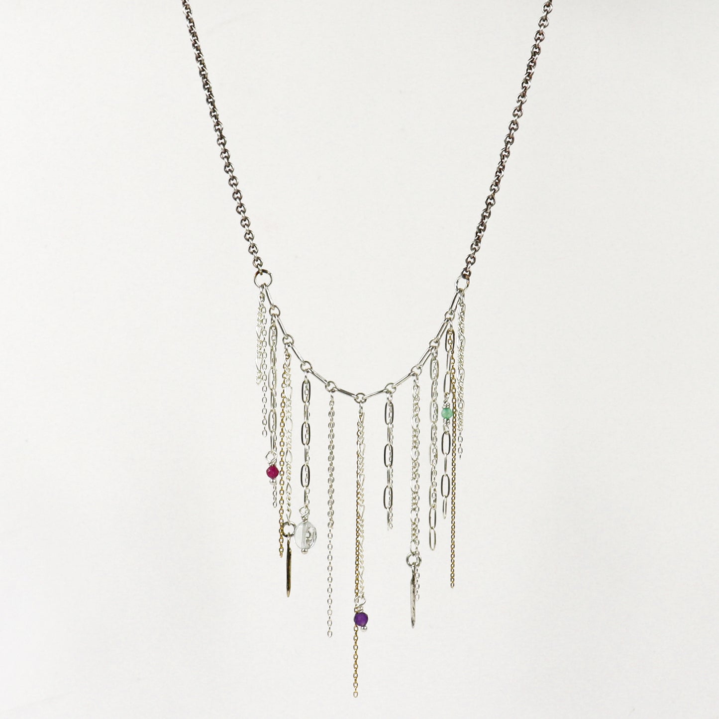 A silver-toned multi-strand fringe necklace handmade by Kria World with dangling chains, paperclip links, and small colorful beads on a plain white background.