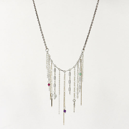A silver-toned multi-strand fringe necklace handmade by Kria World with dangling chains, paperclip links, and small colorful beads on a plain white background.