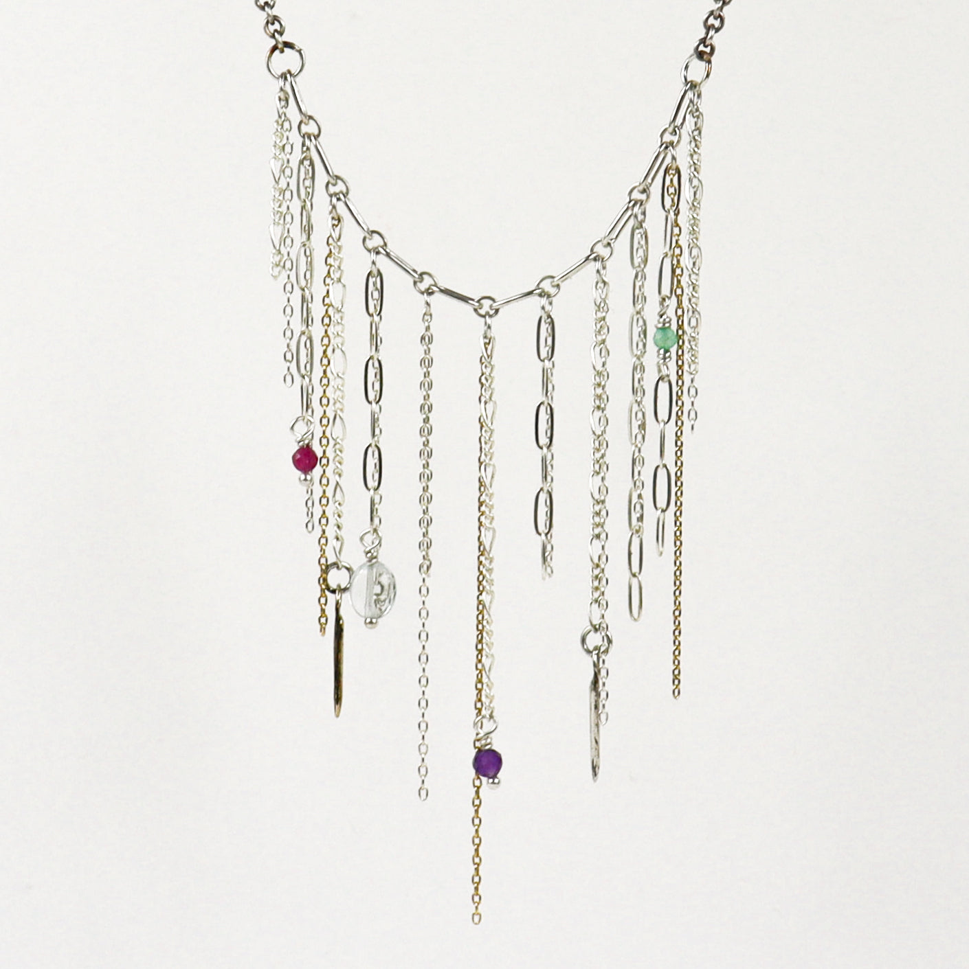 A silver-toned multi-strand fringe necklace handmade by Kria World with dangling chains, paperclip links, and small colorful beads on a plain white background.
