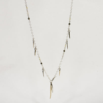Sterling silver front clasp necklace beaded with pyrite, freshwater pearl, and brass and sterling silver spikes by Kria World shown on a white background.