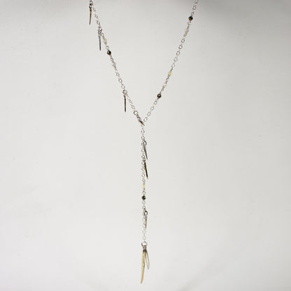 Sterling silver front clasp necklace beaded with pyrite, freshwater pearl, and brass and sterling silver spikes by Kria World shown on a white background.