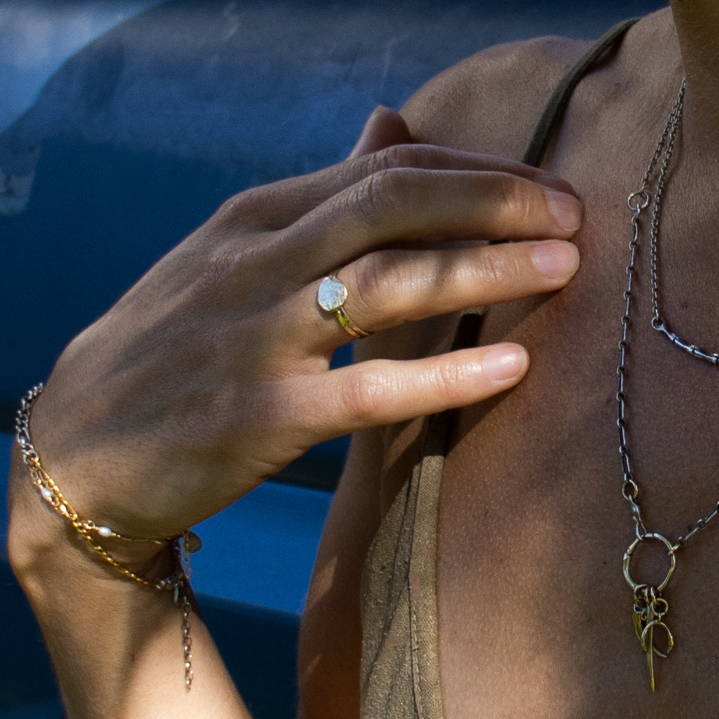 Solid reclaimed 10k gold hammer-finished Maine rock ring with 0.5 inch diameter face handmade and finished in our Catskills store-studio shown on model with necklace and bracelets.