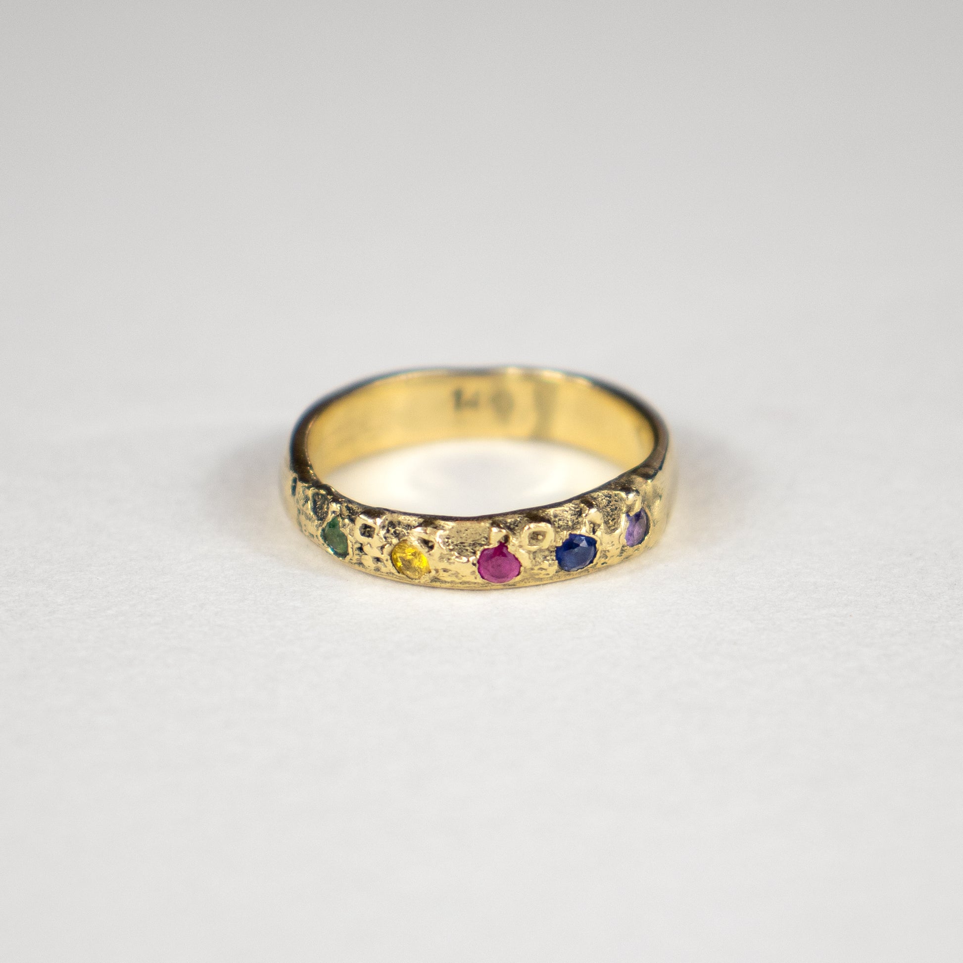 Solid reclaimed 14k gold Vomer ring with 4mm band-width set with five 2 mm rainbow green, yellow, pink, blue and purple sapphires.