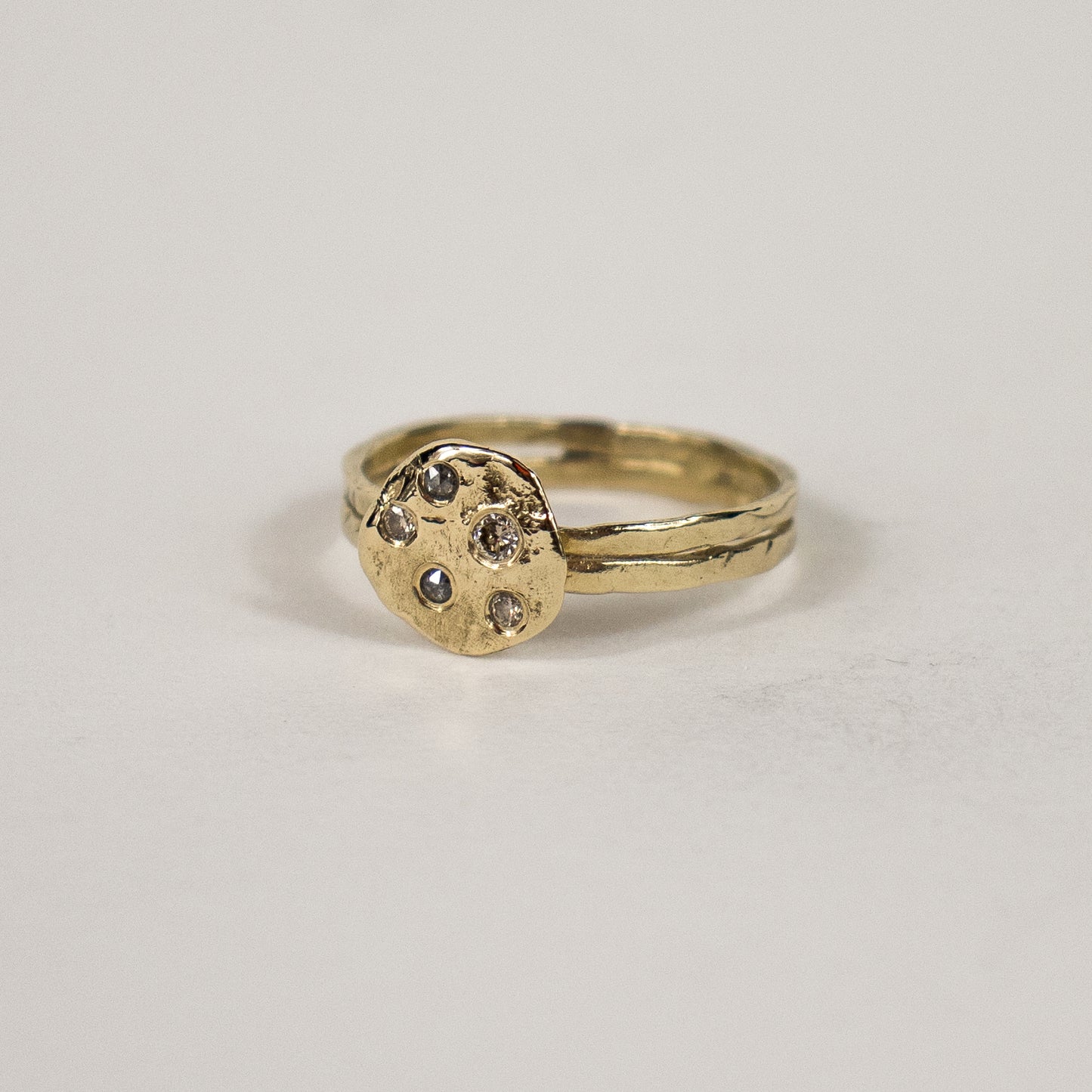 Solid reclaimed 14k gold hammer-finished Maine rock ring set with one 2 mm champagne, two 1.5 mm champagne and two 1.5 mm salt and pepper diamonds with ring face 0.5 inch in diameter.