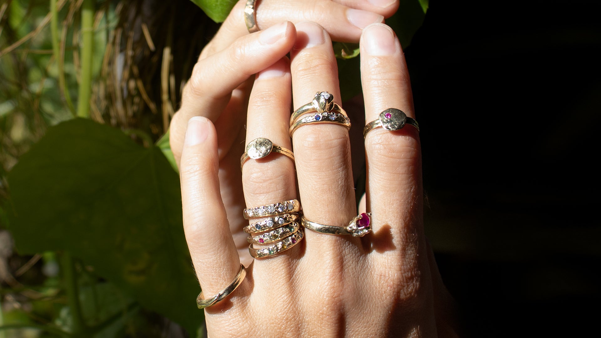 Closeup of model's hands wearing a dozen Kria 14k gold rings set with precious stones handmade with reclaimed gold and finished in our Catskills store-studio by NewYork-based Icelandic designer, Johanna Methusalemsdottir.