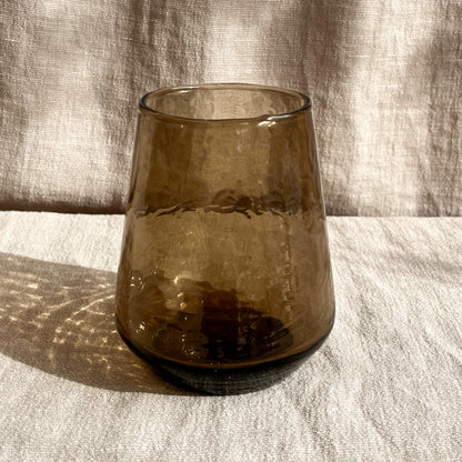 Hand-blown hammered glass tumblers in blush or smoke tints and measuring 4 inches in height and 3 inches in diameter at the base.