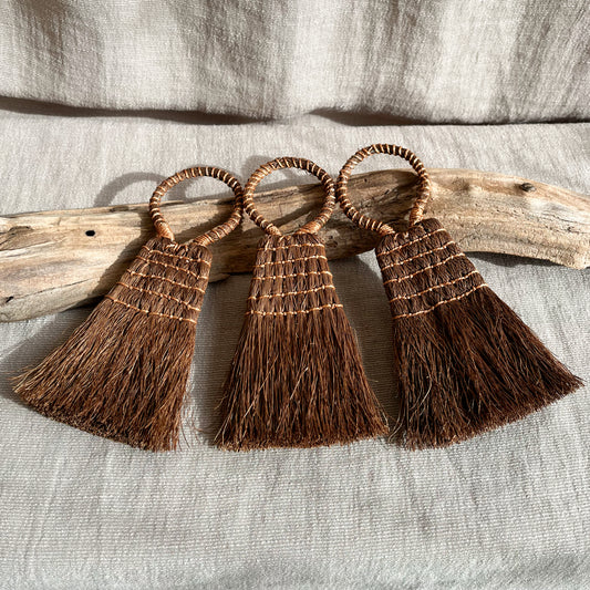 Handmade hand brush made with sustainably sourced palm fibers measuring 5 inches in length and 3 inches in width.